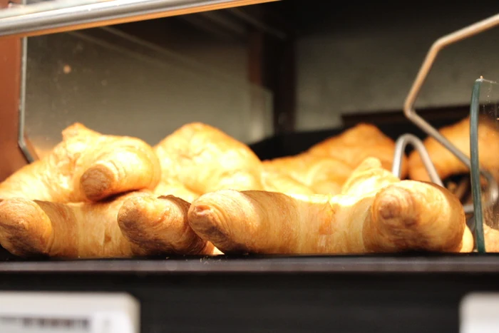 Mehrere goldbraune Croissants in einer beleuchteten Auslage.