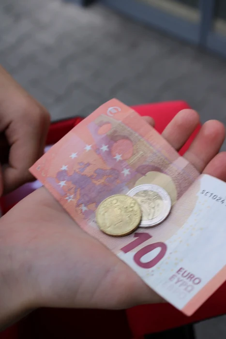 Eine offene Hand hält einen Zehn-Euro-Schein, zwei Münzen und einen Beleg.