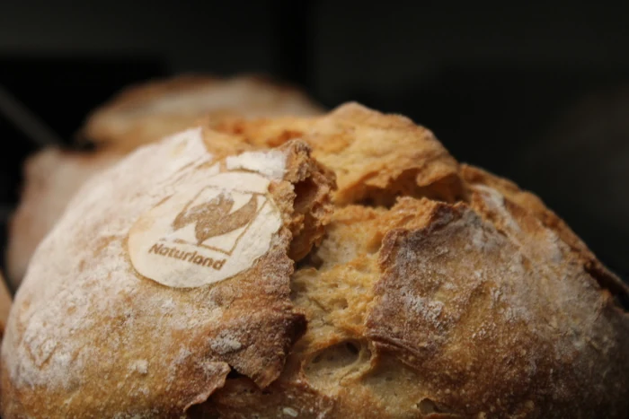 Ein rundes Brot mit heller Mehlkruste und einer kleinen Backmarke.